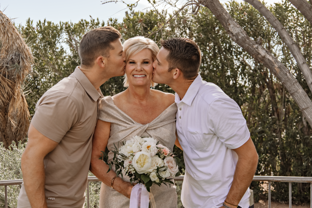 the bride taking picture with her two sons during her backyard wedding