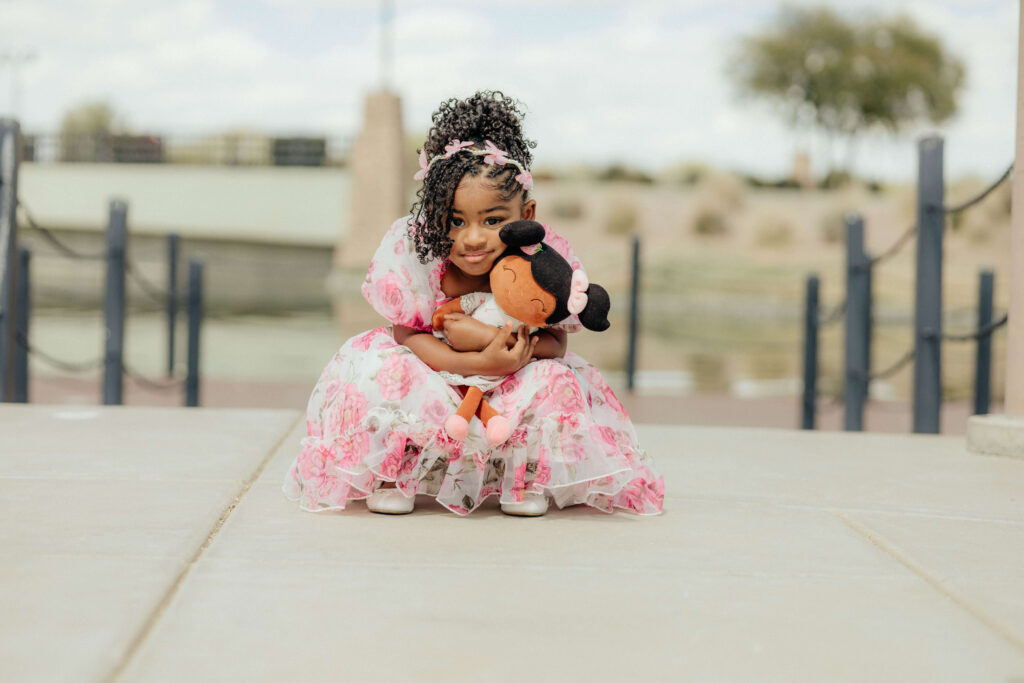 a 3 year old girl holding her doll and bending down